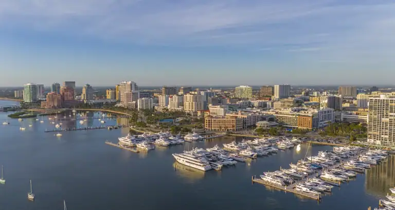 Aerial view of a city skyline with a marina and boats on the water.